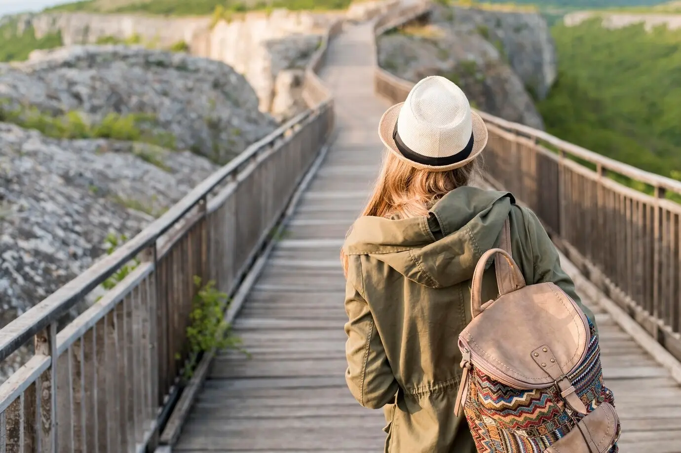 Rear view of a stylish traveller wearing a hat, walking.